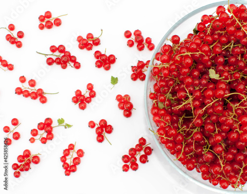 A large bowl of red currants with juicy bunches scattered around.