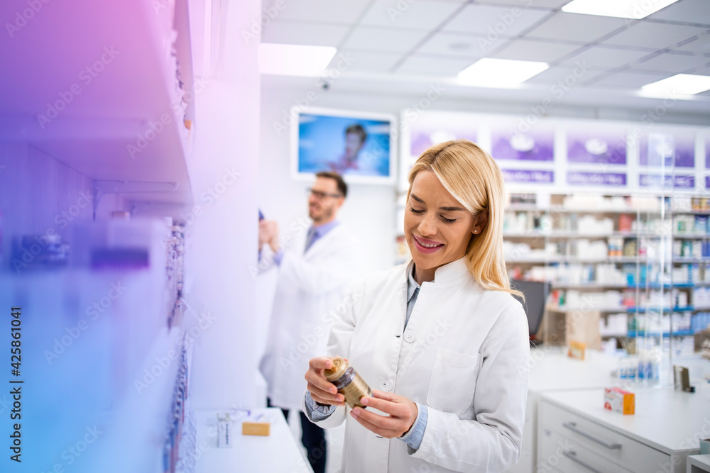 Female pharmacist holding bottle of vitamins if drug store and selling medicines. Female pharmacist holding bottle of vitamins if drug store and selling medicines.