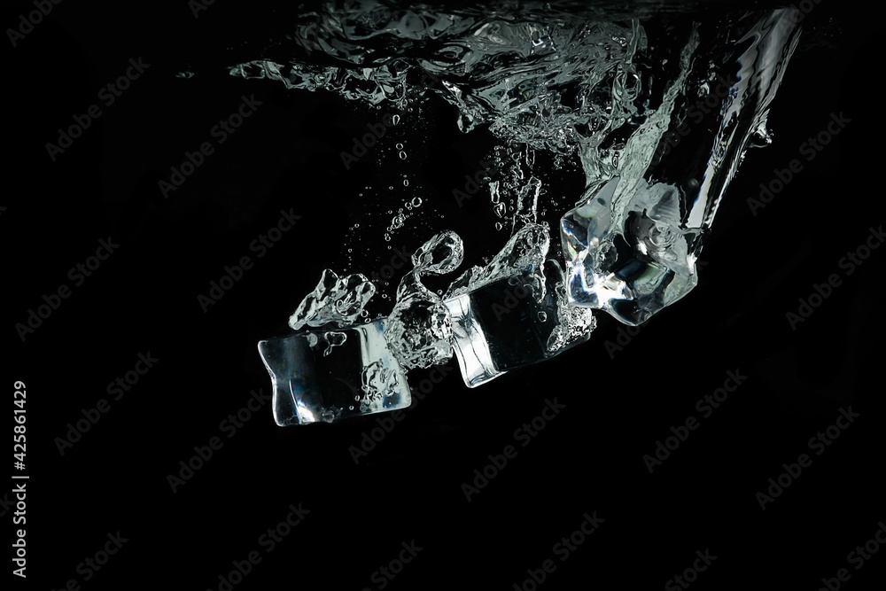 ice cubes fall into the water on a black background. Water splash and air bubbles under the water. ice cubes fall into the water on a black background. Water splash and air bubbles under the water.