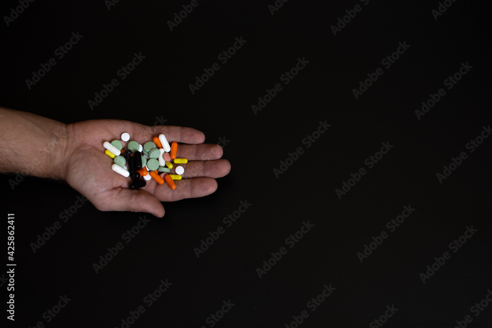 a handful of pills in my hand. tablets in a man's hand on a black background. Close-up. a handful of pills in my hand. tablets in a man's hand on a black background. Close-up.