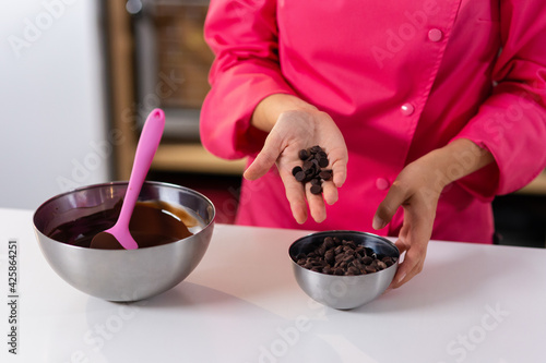 Dark chocolate drops. The concept of tempered chocolate confectionery. Cooking chocolates by homemade confectioners. Business idea. Liquid chocolate. hands, table and kitchen