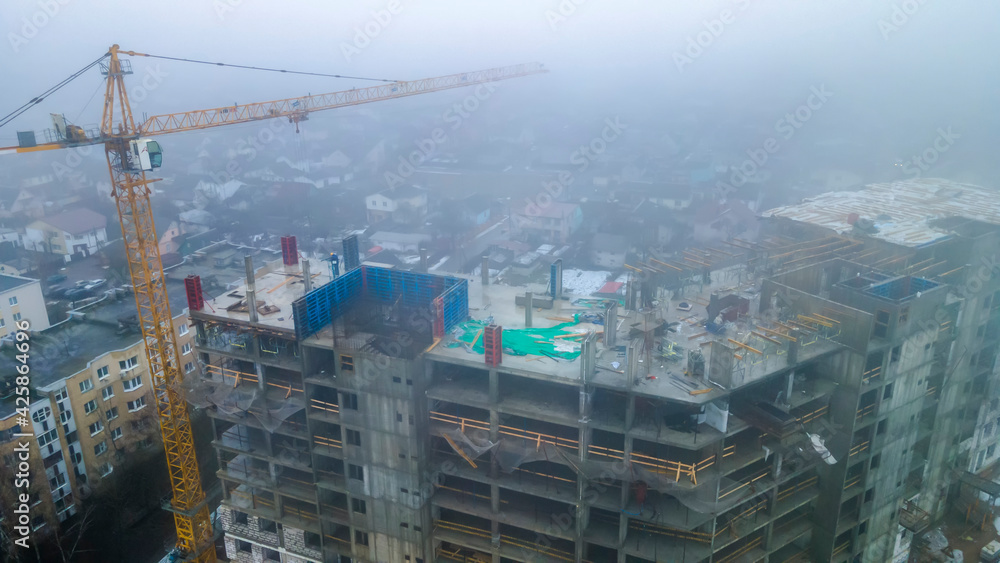 Tall construction crane in the fog. Construction buiding in the mist. Industry concept.