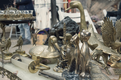 Antiques on flea market or festival - vintage silver and cooper statuettes and other vintage things. Collectibles memorabilia and garage sale concept. Selective focus