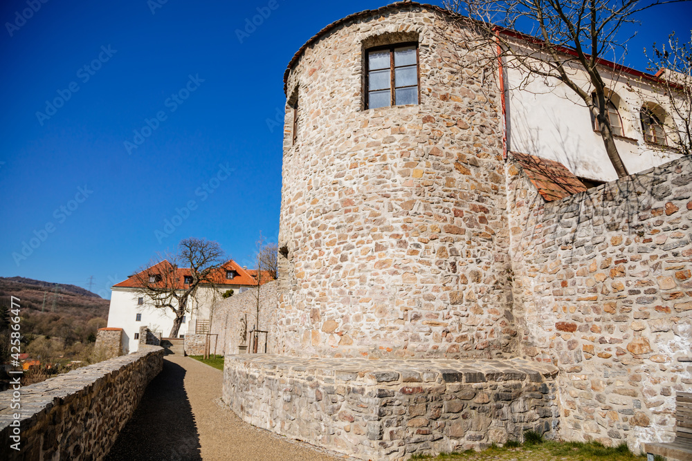 Medieval gothic town fortification, fortress wall on sunny day at the top of the hill, old stronghold, antique masonry, renaissance historical buildings, Kadan, Czech Republic