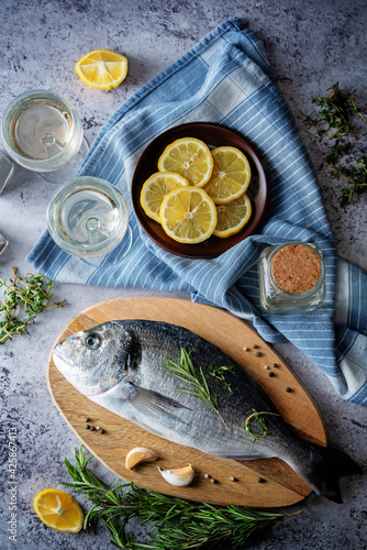 Raw fresh dorada fish with lemon slices and greens photo