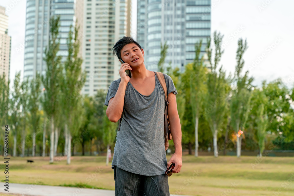 Young asian guy talking on the phone in a park