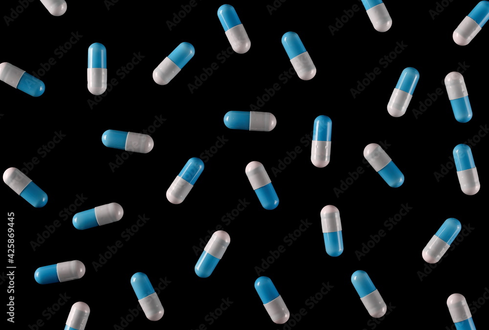Blue white pills isolated on black background and texture, top view Blue white pills isolated on black background and texture, top view