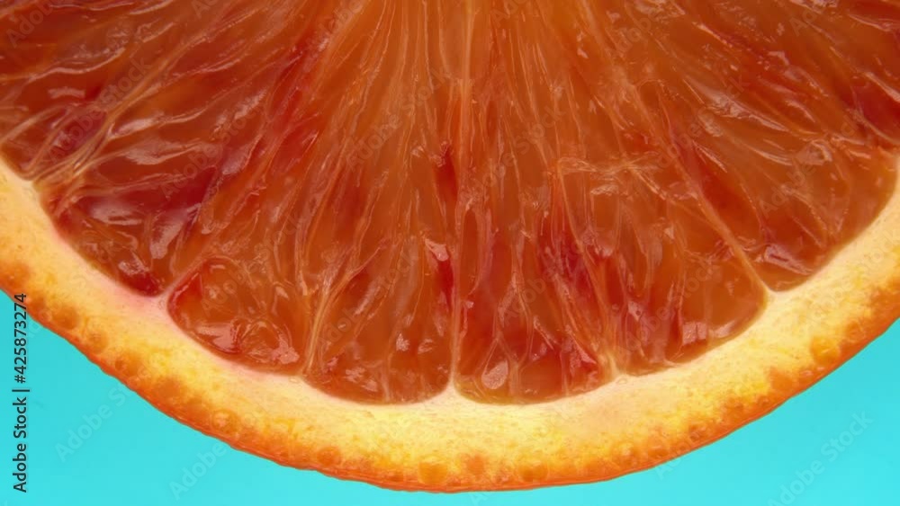 Macro details of a blood orange slice rotating top view on light blue background.Macro food.Looped rotation.Healthy eating concept.Organic fresh harvest.healthy food,bio food.red fruit Macro details of a blood orange slice rotating top view on light blue background.Macro food.Looped rotation.Healthy eating concept.Organic fresh harvest.healthy food,bio food.red fruit