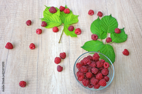 Fresh raspberries on wooden background, close up of berries juicy ripe fruit and leaves