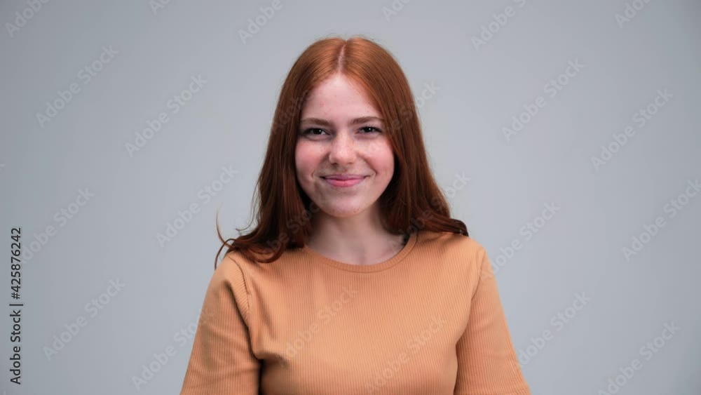 Beautiful ginger woman with red hair and freckles shows an air kiss smiling kissing face emotion isolated on grey studio background. Party, happiness, freedom, youth concept. Beautiful ginger woman with red hair and freckles shows an air kiss smiling kissing face emotion isolated on grey studio background. Party, happiness, freedom, youth concept.