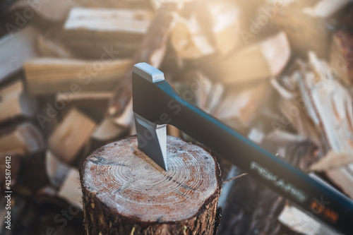 Detail of axe. Axe and firewood. Sharp ax standing on a wooden, tree stump on a background of chopped wood.