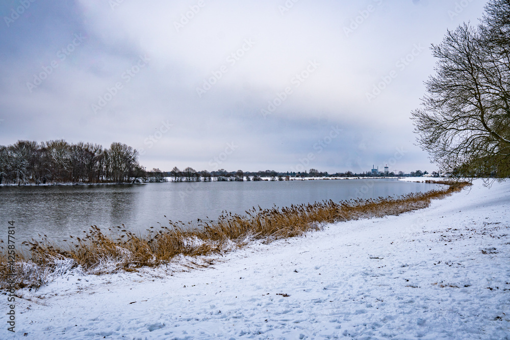 beautiful, almost frozen river called werdersee at cold white winter with snowy dike in bremen beautiful, almost frozen river called werdersee at cold white winter with snowy dike in bremen