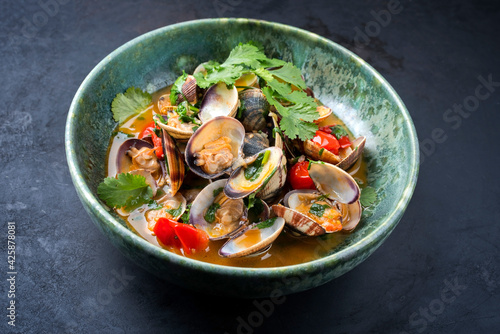 Modern style traditional Italian venus clams soup with tomatoes and garlic in a wine jus as close-up in a Nordic design bowl