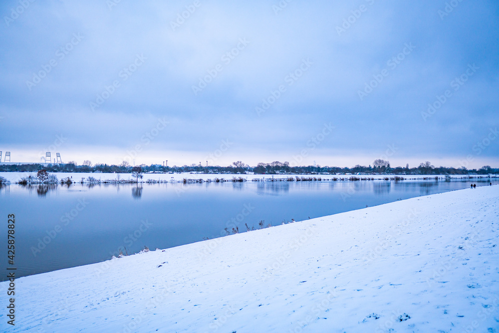 beautiful, almost frozen river called werdersee at cold white winter with snowy dike in bremen