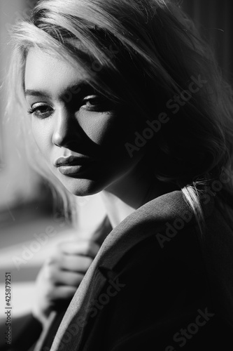 Close up portrait of beautiful young girl in the rays of sun. Shadows on her face. Black and white concept