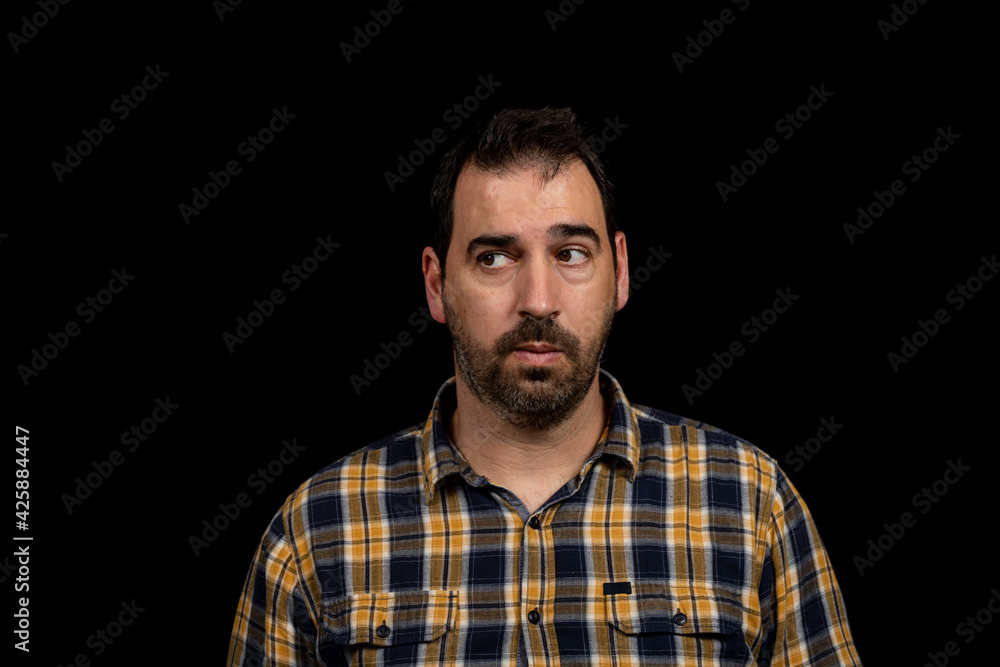 Portrait of bearded man in yellow checkered shirt on black studio background