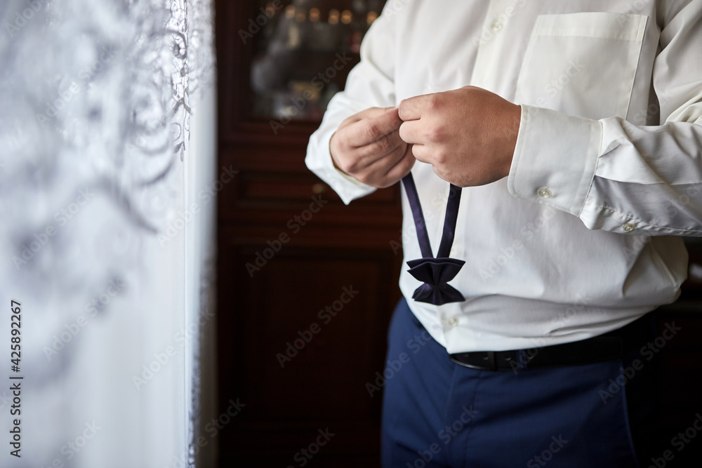 Obraz premium businessman putting on bow tie,man butterfly clothes,groom getting ready in the morning before wedding ceremony. Men Fashion