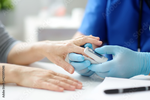 A woman at a doctor s appointment during the coronavirus epidemic. Doctor checking oxygenation with fingertip pulse oximeter. Saturation blood of oxygen.