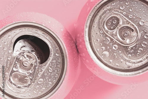 Pink soda cans in water drops, top view