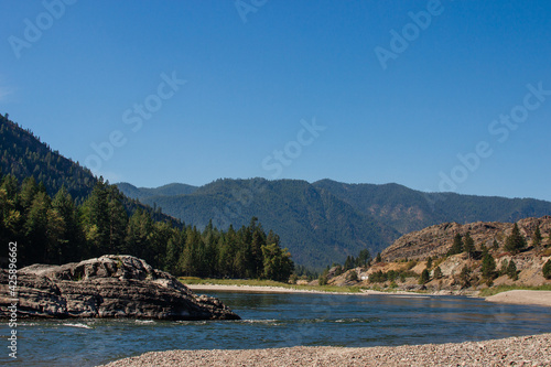 Beautiful landscape with mountains, forest, river with big rocks, and blue clear sky on sunny summer day. Rest Area, I-90, Alberton, MT, USA