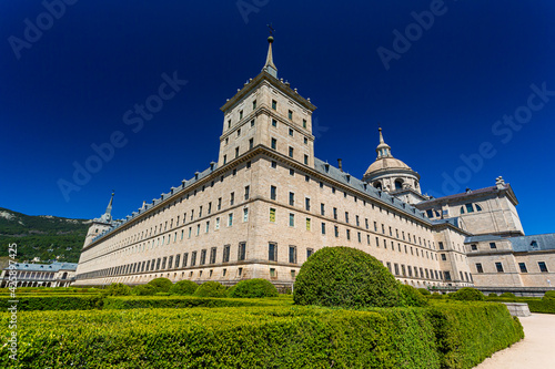 El Escorial, Spain- March 17, 2021: Monastery of El Escorial. Facade with parade ground and gardens of the Escorial Monastery. Spanish Royal Palace. National Heritage. Culture of the Spanish royalty.
