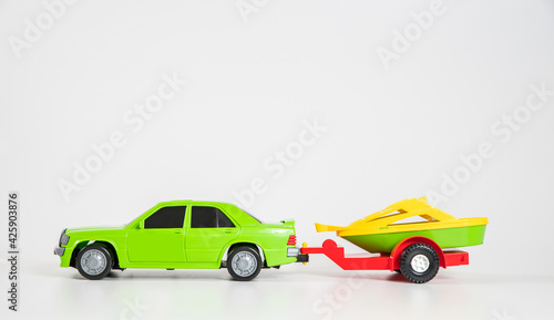 Children s toy plastic car isolated on white background. Multi-colored passenger car with a trailer for transporting a motor boat.