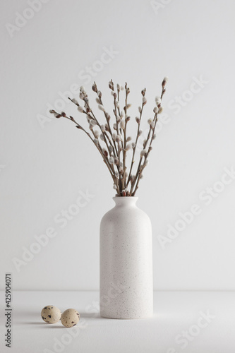 Easter eggs and a bouquet of willow trees in a vase on a white background