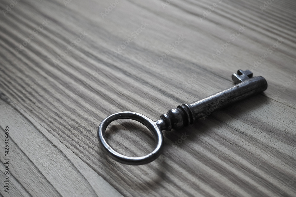 Iron key on a textured wooden table, background Iron key on a textured wooden table, background