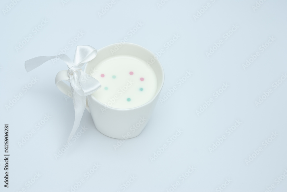 White cup of milk with a bow on a white background White cup of milk with a bow on a white background