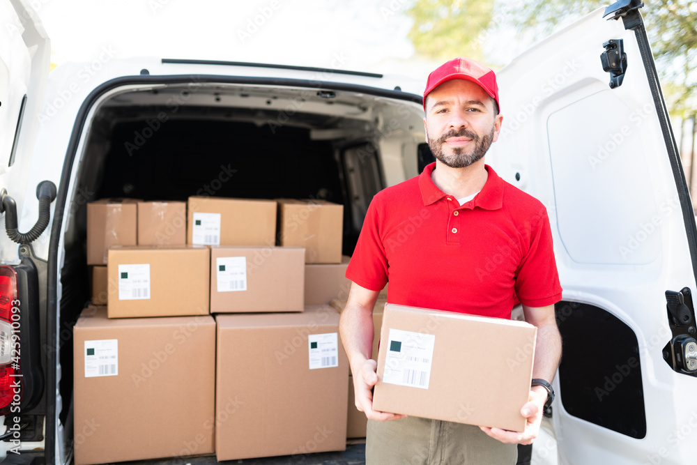 Hispanic man delivering a package in a delivery van Hispanic man delivering a package in a delivery van