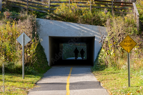 Fototapeta Cyclists Pass Through Tunnel on a Biking Path