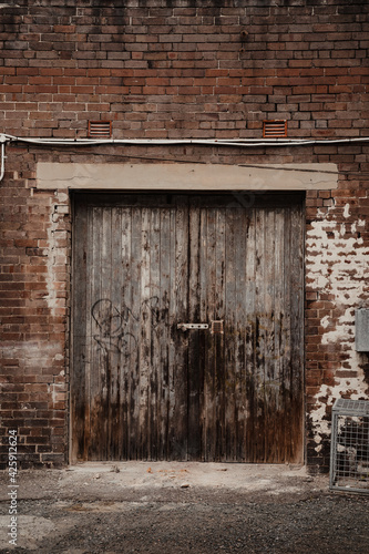 Old grunge wooden door with dark red-brown brick surrounding