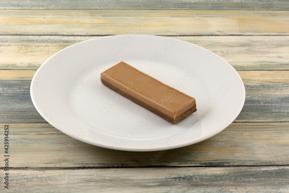 Two layered and flavored nougat and chocolate hazelnut nougat candy bar on white plate Two layered and flavored nougat and chocolate hazelnut nougat candy bar on white plate