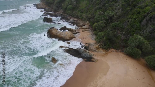 Waves Splashing On The Rocks At The Shore With Lush Vegetation. Bonville Headland In New South Wales, Australia. aerial drone photo