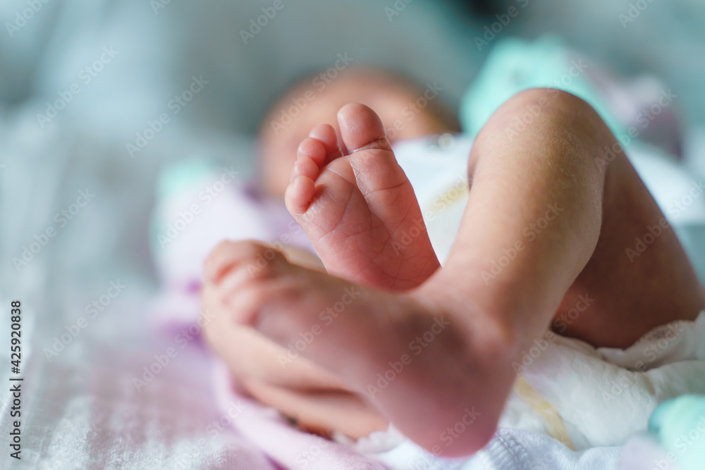 Close up on feet of unknown baby newborn lying on bed at home with copy space Close up on feet of unknown baby newborn lying on bed at home with copy space