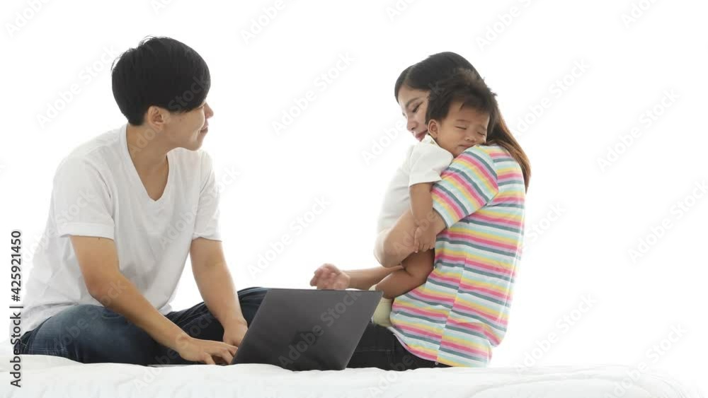 Younger embracing child sitting on bed with elder lesbian in bedroom on white background. Happy LGBT family concept Younger embracing child sitting on bed with elder lesbian in bedroom on white background. Happy LGBT family concept
