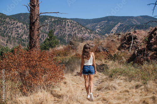 A young woman walks along a path among the dry grass. Beautiful landscape with mountains, forest and large rocks on a sunny day. Recreation Area, I-90, Alberton, Montana, USA 9-3-2020