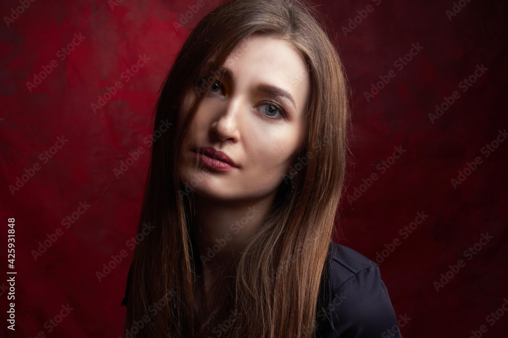 Portrait of a young woman with long brown hair, on a red textured background