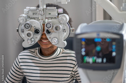 фотографія Close-up Of african teen girl Doing Eye Test On Phoropter, African teen girl checking on her eye with optometry machine