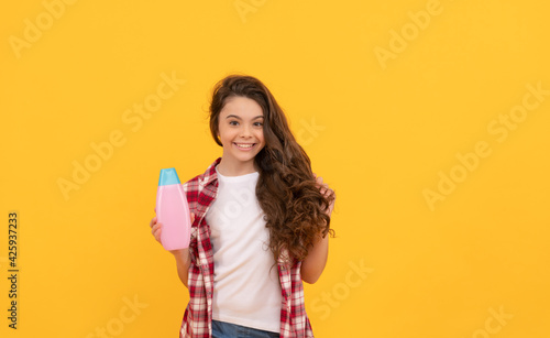 beauty. kid use shower gel. happy teen girl with shampoo bottle. shampooing hair in salon