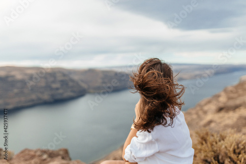 Young woman in blue shorts and a white shirt against the backdrop of a beautiful landscape with a large river and mountains. Colorado river, USA