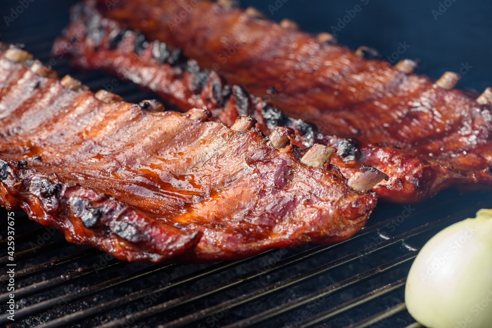 Close up of two racks of pork BBQ ribs brushed in BBQ sauce on a smoker grill Close up of two racks of pork BBQ ribs brushed in BBQ sauce on a smoker grill