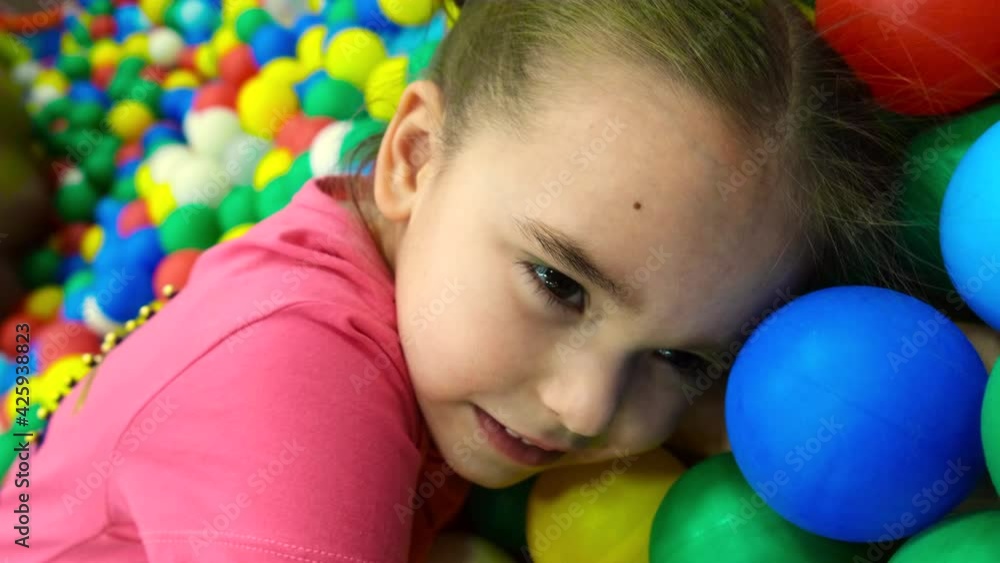 a child in the children's playroom. The girl is having fun among the colorful balls. Dry Pool Party a child in the children's playroom. The girl is having fun among the colorful balls. Dry Pool Party