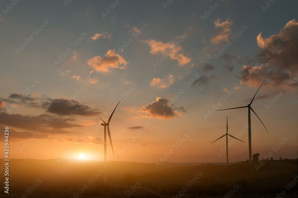 Obraz premium Silhouette of wind turbines at sunset.