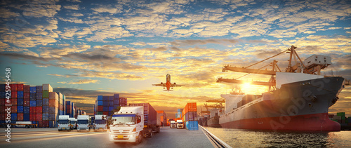 Container truck in ship port for business Logistics and transportation of Container Cargo ship and Cargo plane with working crane bridge in shipyard at sunrise, logistic import export  concept