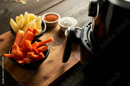 Cooking potatoes and carrot sticks with spices in an air fryer