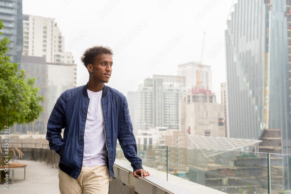Portrait of handsome black African man at rooftop garden thinking Portrait of handsome black African man at rooftop garden thinking
