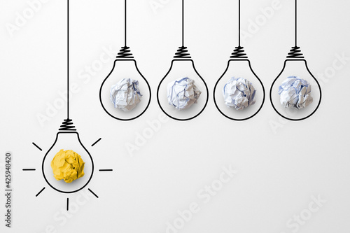 Concept creative idea and innovation. Paper scrap ball yellow colour outstanding different group with light bulb symbol photo