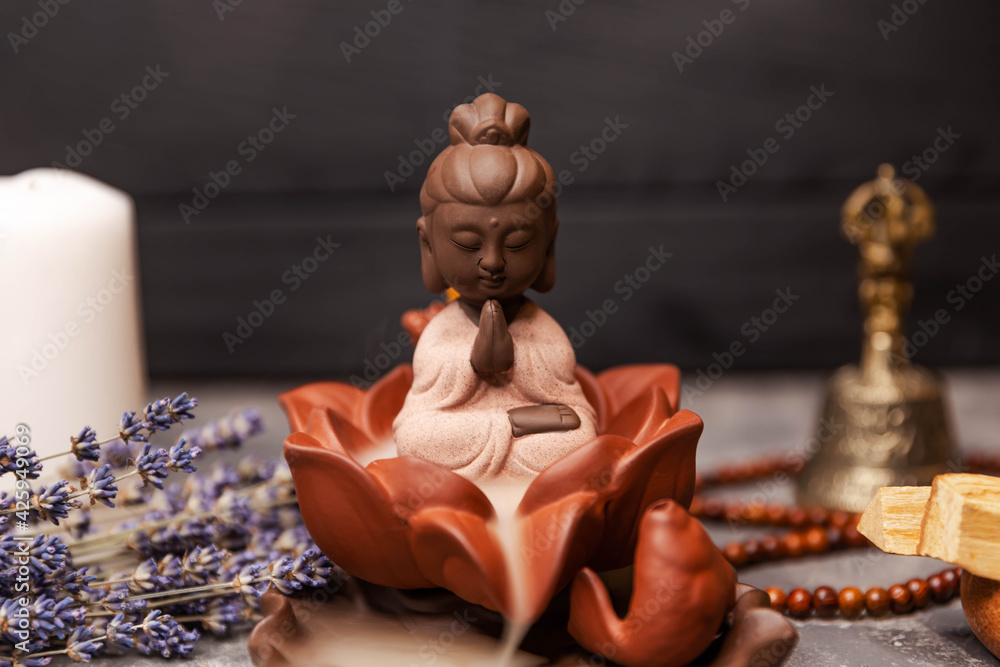 Spa and aromatherapy. Ceremony of worship of the Buddha. Incense sticks. Buddha figure on grey board with an aroma smoke from burning incense sticks flutters on the background. Herbal medicine