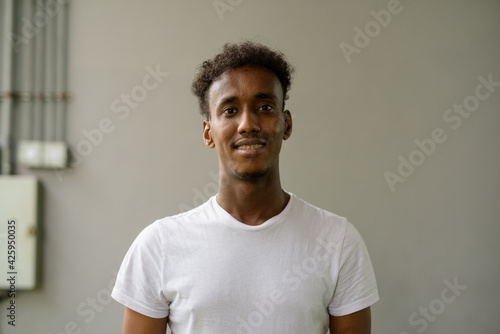 Portrait of handsome black African man with cool attitude against plain wall background